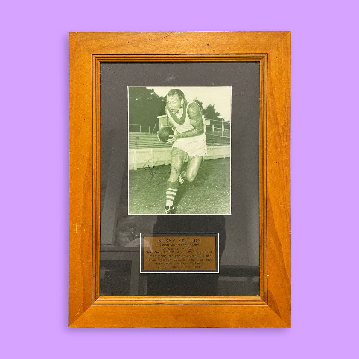 Framed black and white photo of a sports player with a wooden frame on a purple background