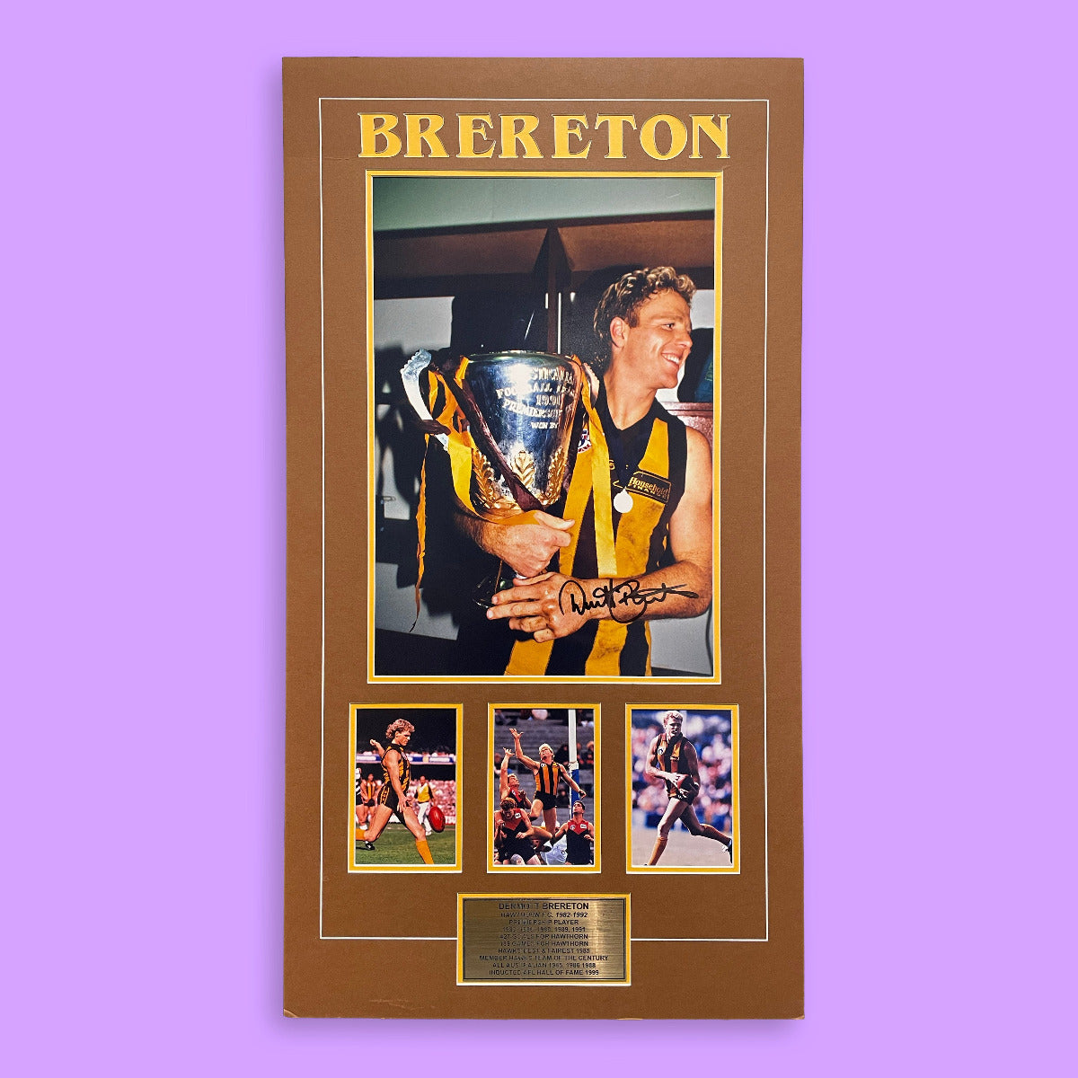 Framed sports memorabilia with a person holding a trophy and multiple images of athletes on a purple background.