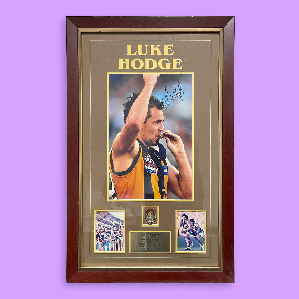 Framed sports memorabilia of Luke Hodge with a purple background