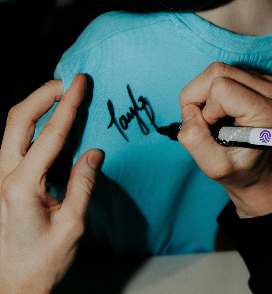 Person writing on a blue shirt with a marker
